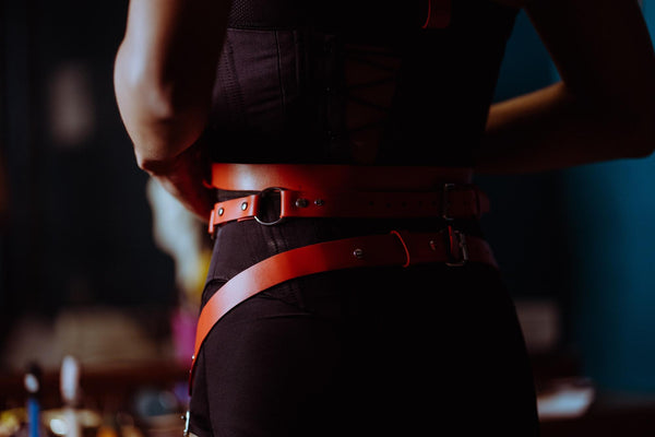 mulher com roupa escura e chicotes vermelhos ao redor da cintura
